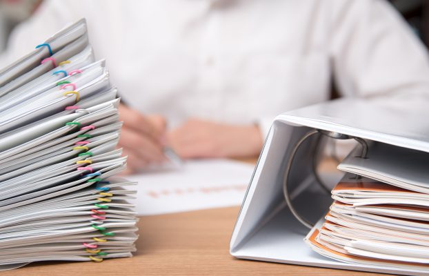 A pile of documents with the man in the document work overload